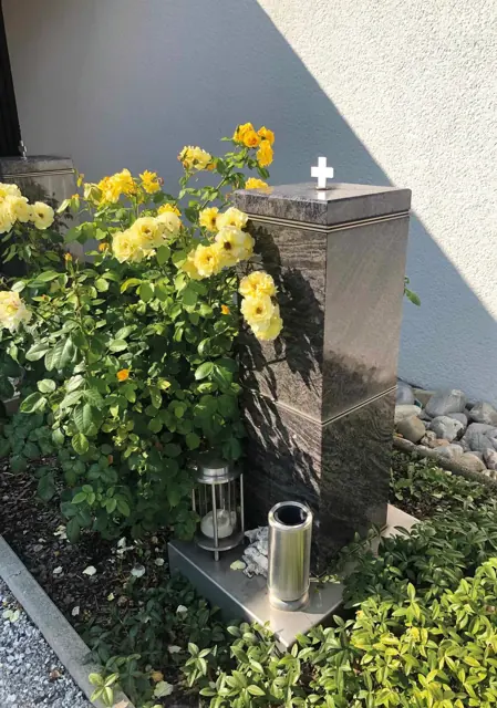 Urnensäule mit Blumen und Erinnerungsstücken